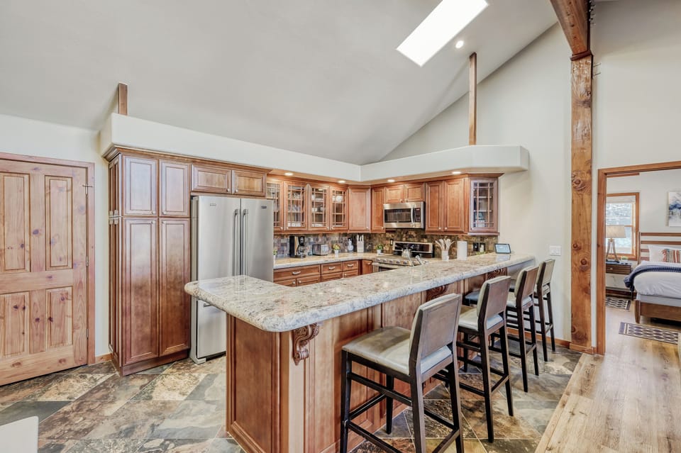 Gather around the expansive granite island in this bright, fully-equipped kitchen where natural light pours through the skylight above. With bar seating for everyone, it's your perfect spot for morning coffee or evening conversations.