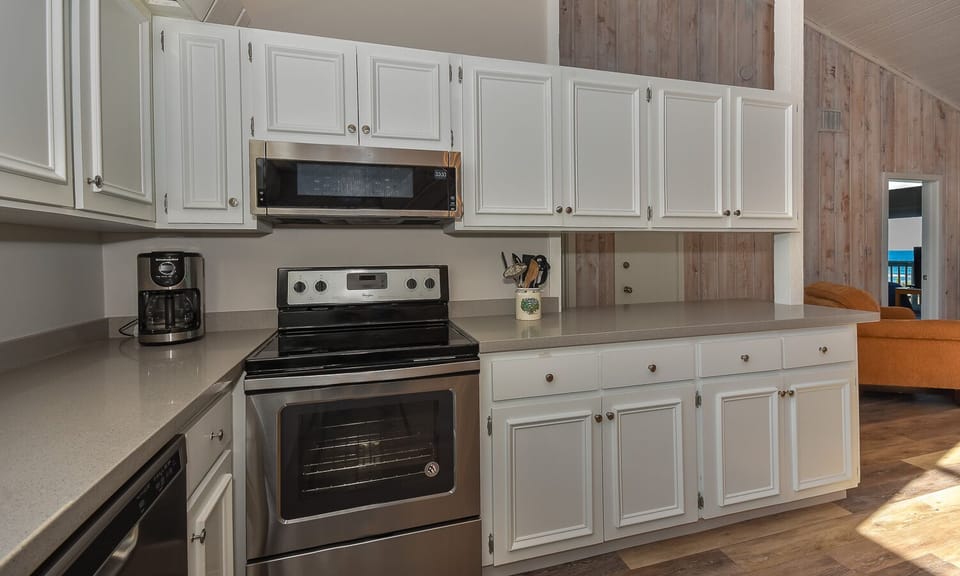 Kitchen with gray countertops, stainless steel appliances, and white cabinets