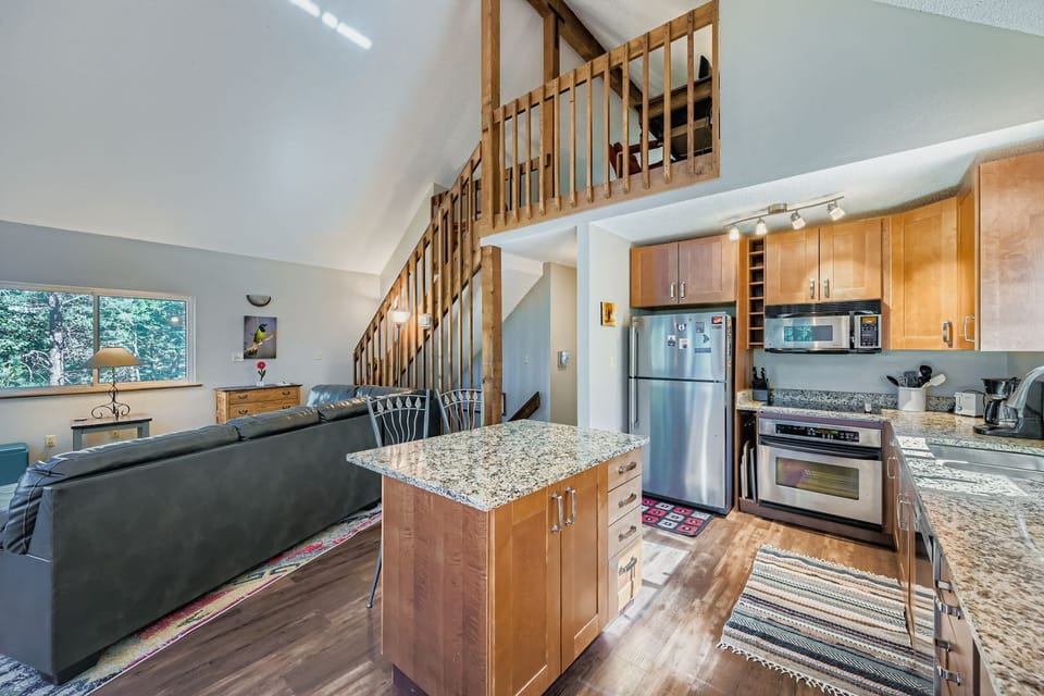 Great room with kitchen and stairs leading to open loft bedroom and lower level