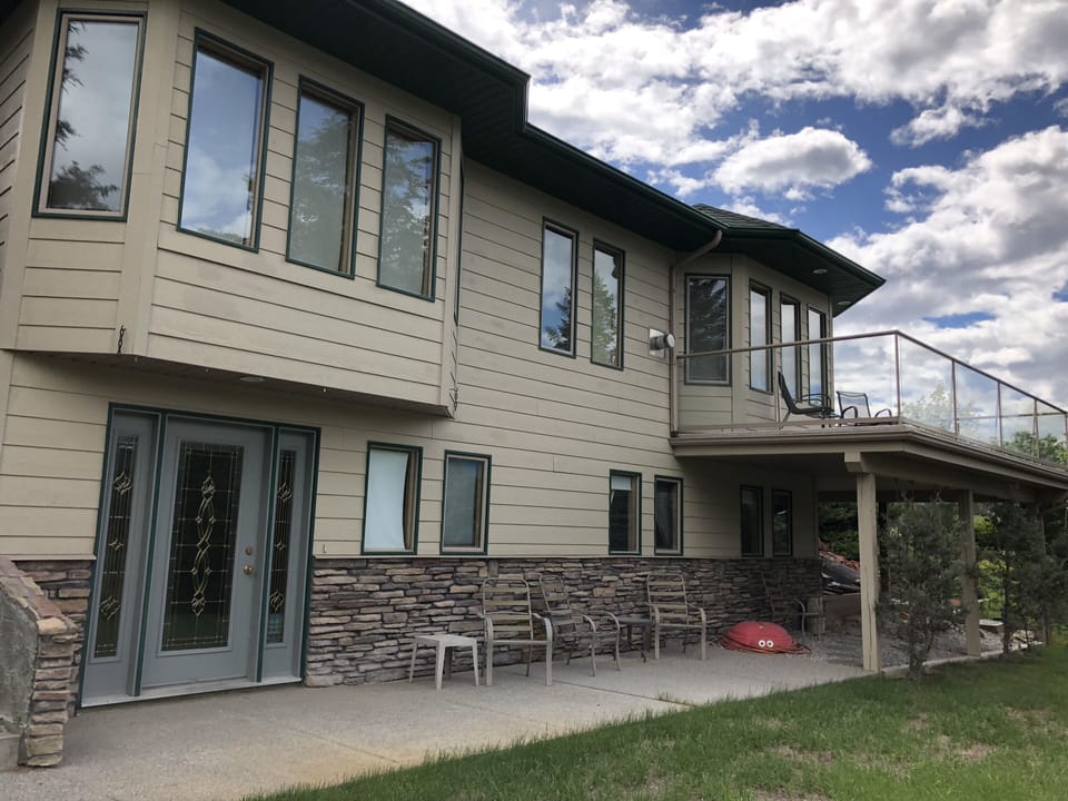 View of home facing the lake, flat lawn, sand box, swings