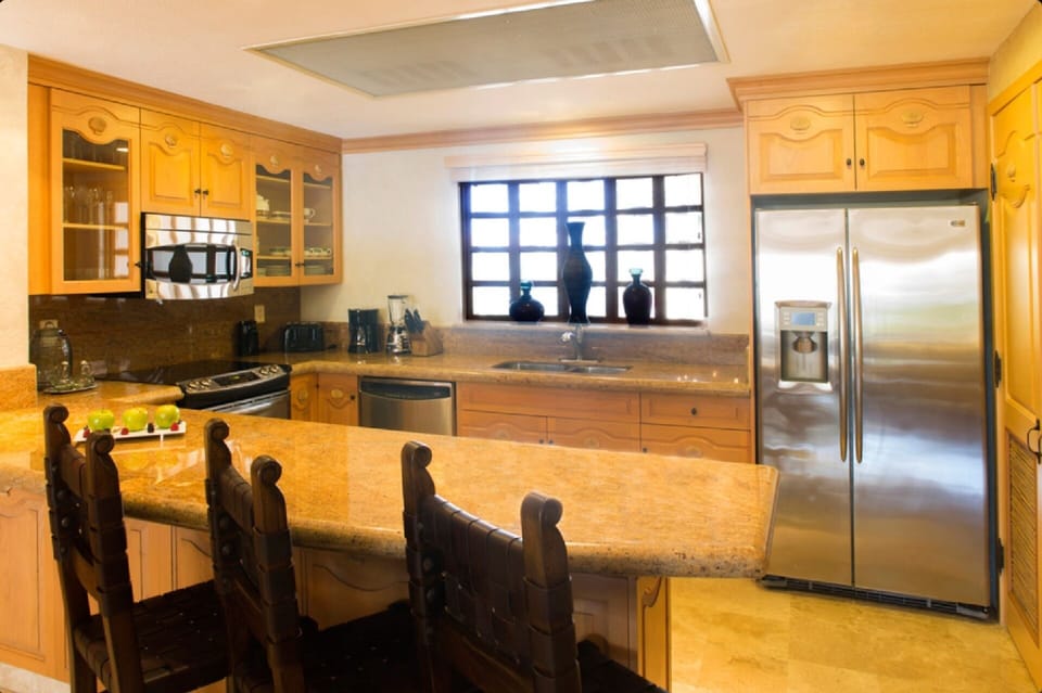 Full kitchen with modern appliances and marble counter tops.