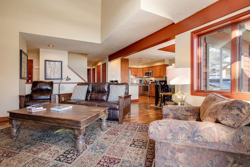 Unwind in this spacious living room where rich wood beams frame your mountain retreat, complete with plush seating and a fully equipped kitchen.