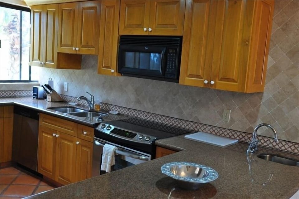 Kitchen w granite countertops, tumbled marble walls, and chef set-ups.