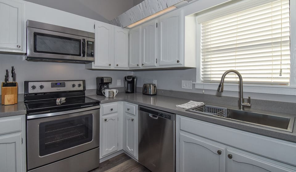Stainless steel appliances in kitchen with white cabinets