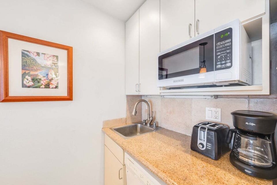 Fully equipped kitchen with microwave, coffee maker, and ample storage.