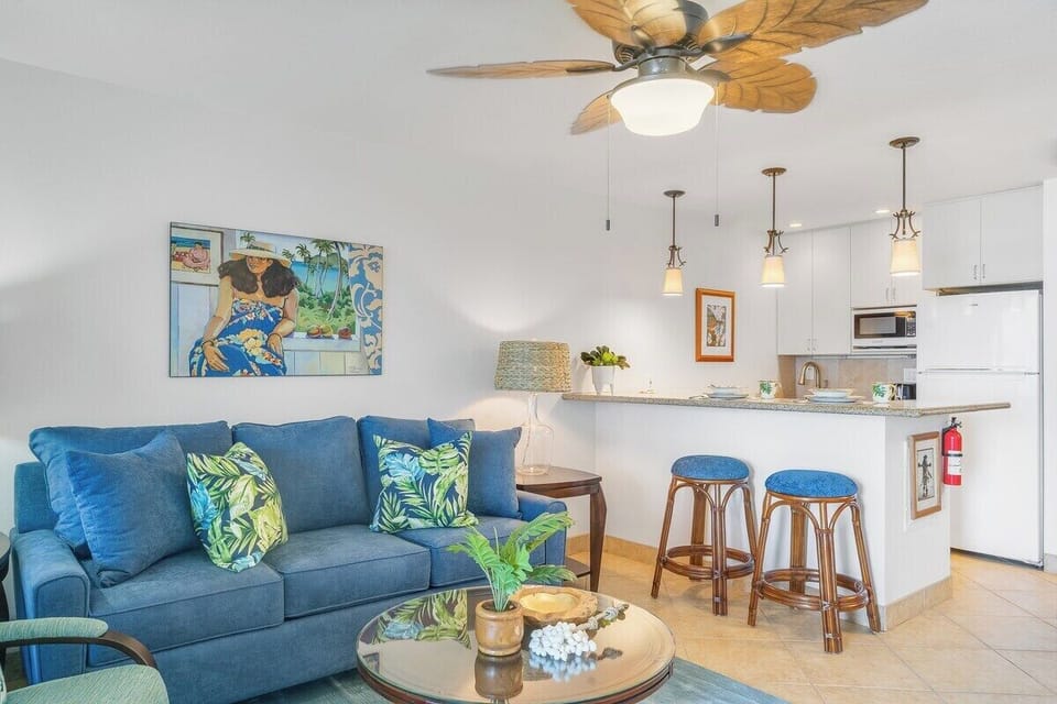 Open living area with blue sofa, ceiling fan, and adjacent dining space.