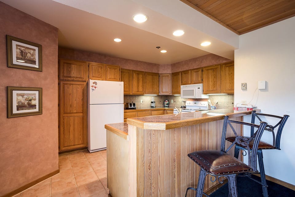 Your fully equipped kitchen features warm wood cabinetry and a breakfast bar where you can savor morning coffee while planning adventures.