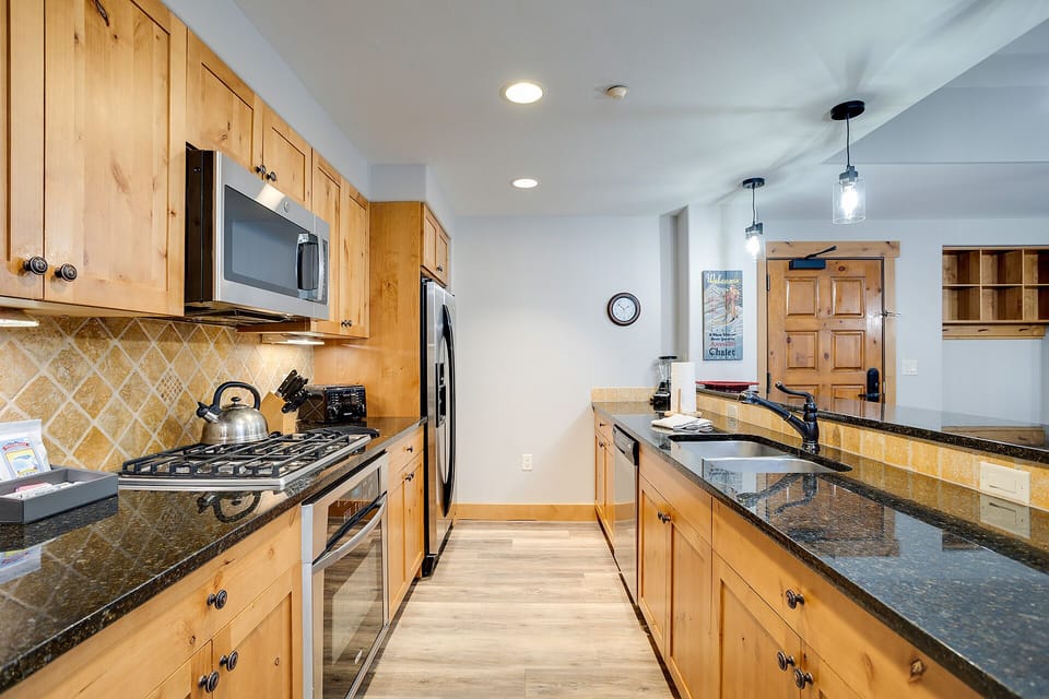 Your fully-equipped kitchen features warm wood cabinets, granite counters, and modern appliances for effortless meal preparation during your stay.