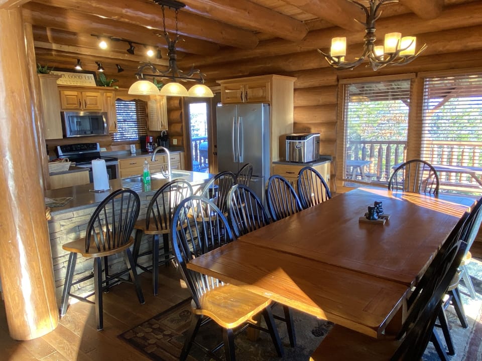 Dining room with fully equipped kitchen behind and covered porch outside.