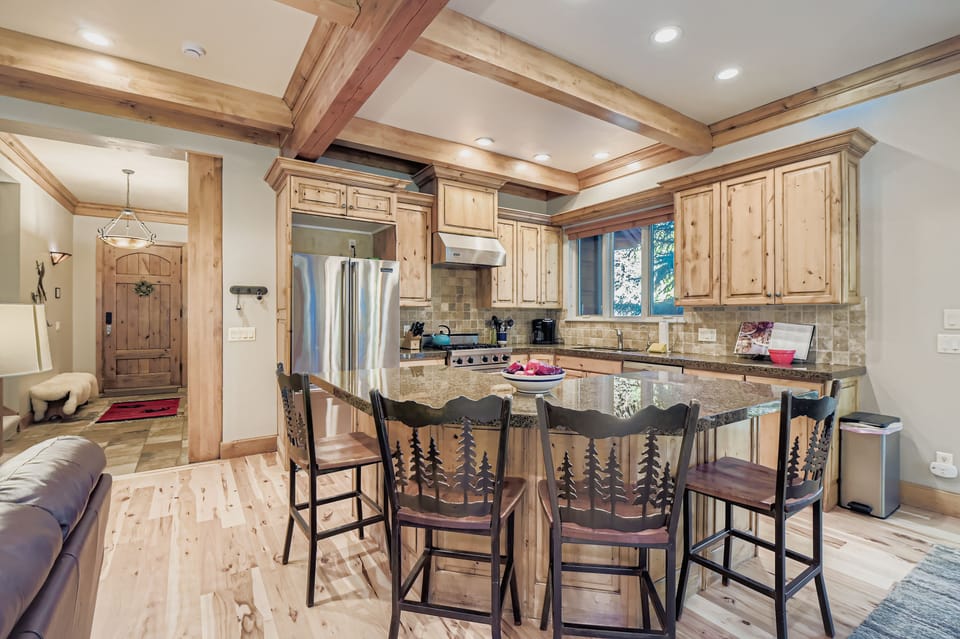 Cook in a gourmet rustic kitchen! Featuring stunning granite countertops, high-end stainless steel appliances, custom knotty-wood cabinetry, and unique bear-themed bar stools.