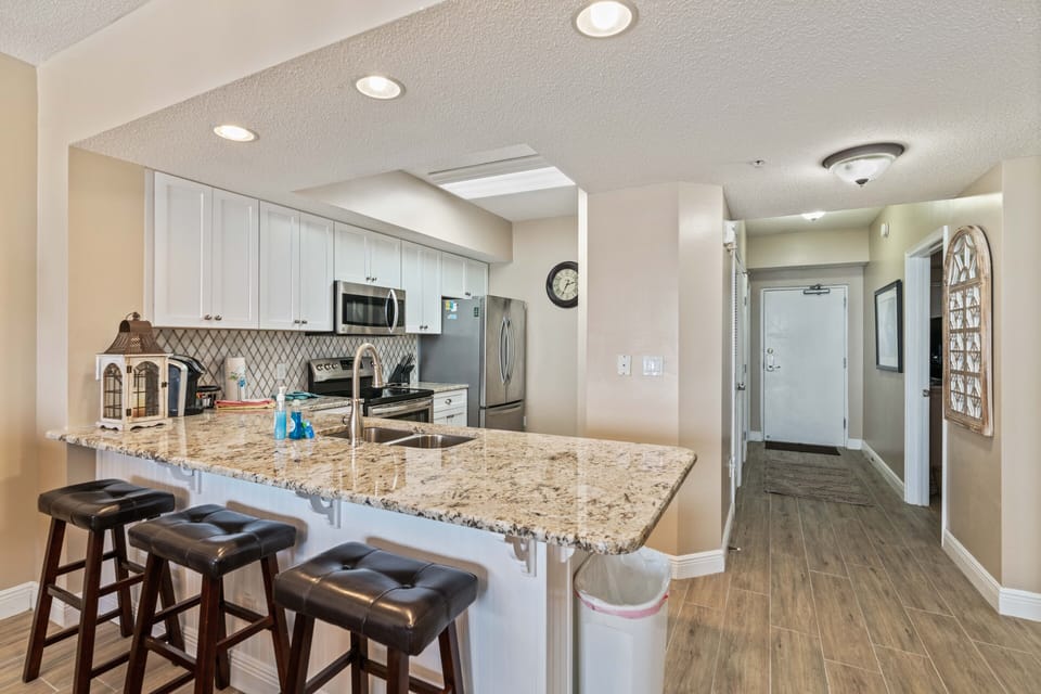 Kitchen with view of entry door and hallway that leads to two front bedrooms.