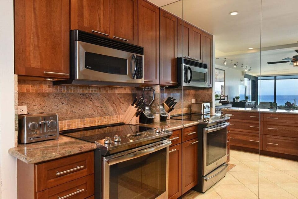 Cook with ease in this modern kitchen featuring stainless steel appliances, mirrored accents, and ocean views
