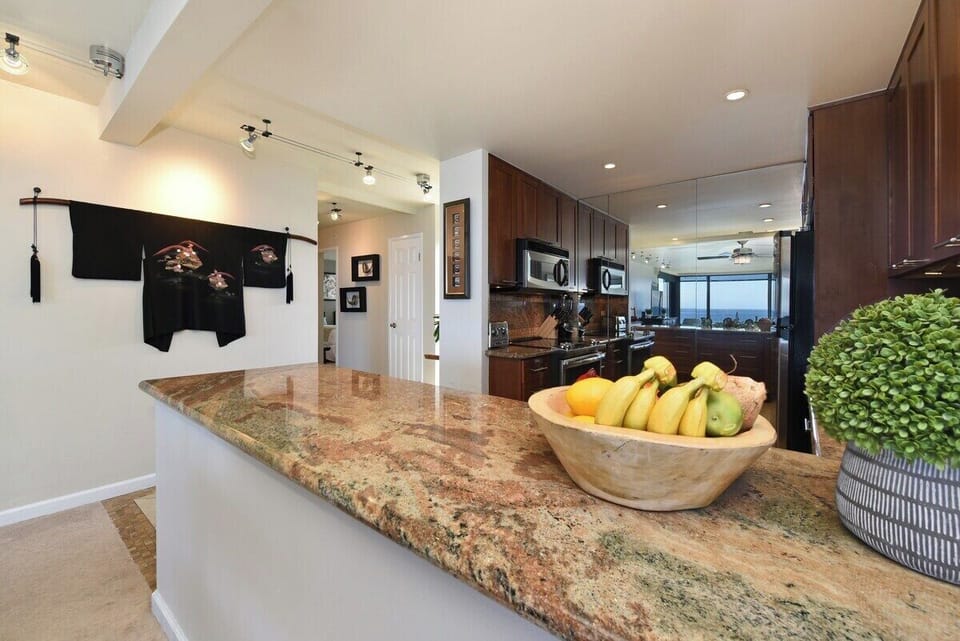 A spacious counter with natural stone finish and fresh accents, perfect for preparing meals in style