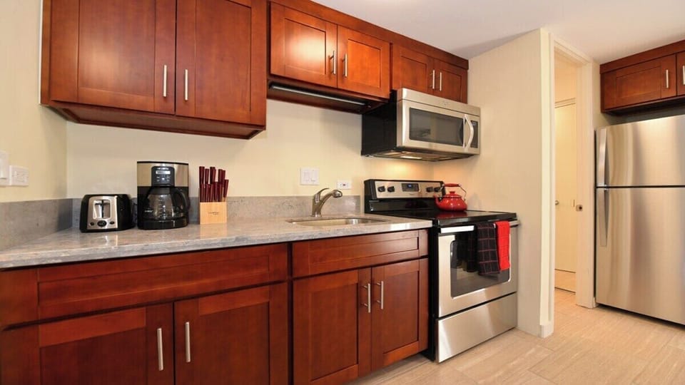 Fully equipped kitchen with warm wood finishes, stainless steel stove and microwave, and a clean, functional design
