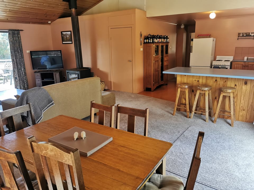 TV and wood heater in living area, dining table and breakfast bar