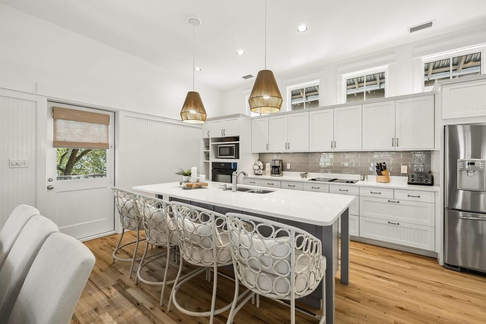 White beadboard kitchen cabinets align with a gray subway tile backsplash and stainless steel appliances.
