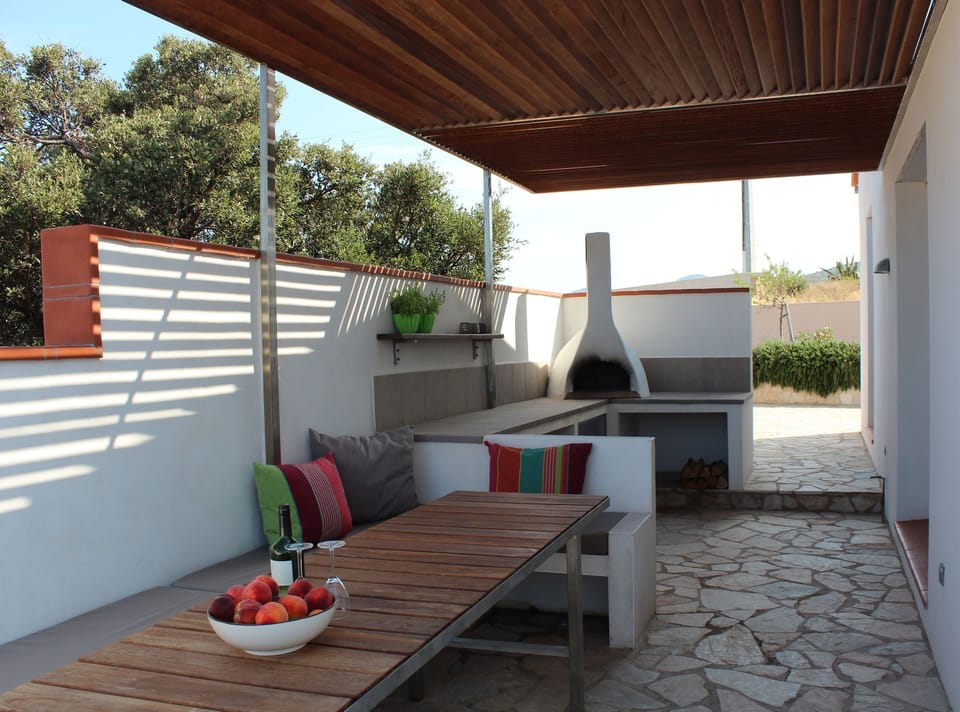 Shaded outdoor dining area and kitchen with pizza oven