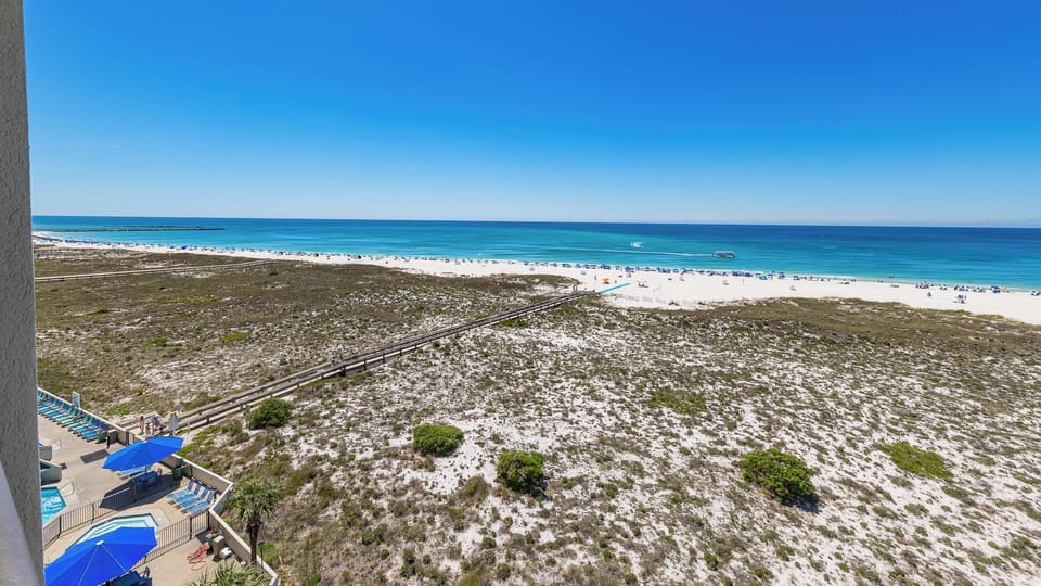 A boardwalk leads you from pools shaded by blue umbrellas to the bright white beach and gentle shore waters