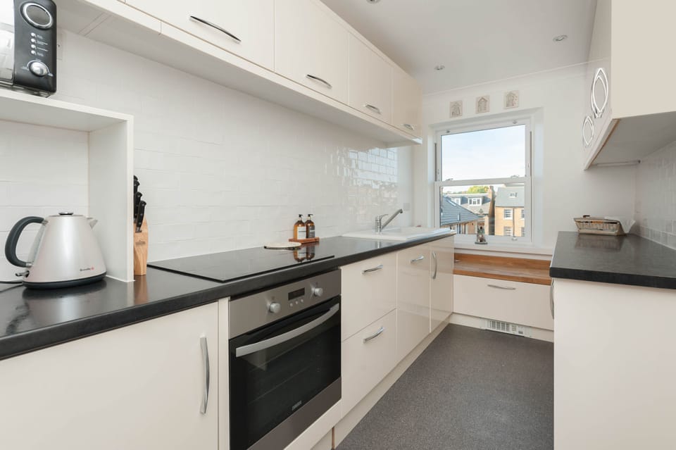 Fully equipped modern kitchen with dishwasher, hob, oven, fridge and cooking essentials