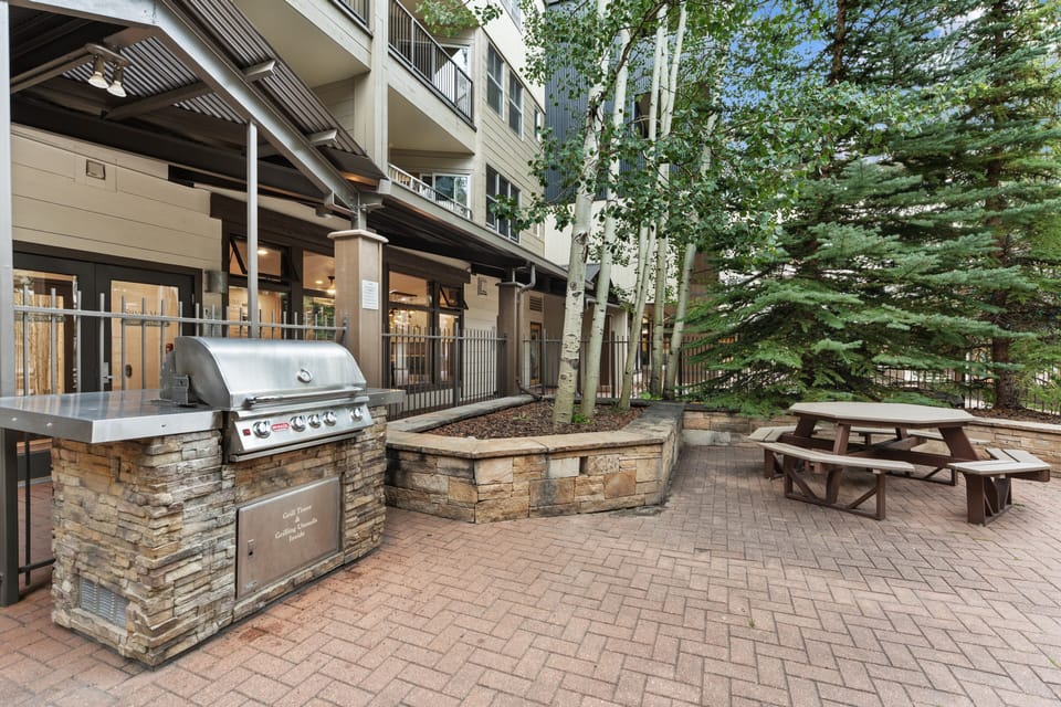 A welcoming outdoor grilling area and picnic pavilion nestled among tall aspen and pine trees, perfect for group gatherings or quiet afternoons in the fresh mountain air.