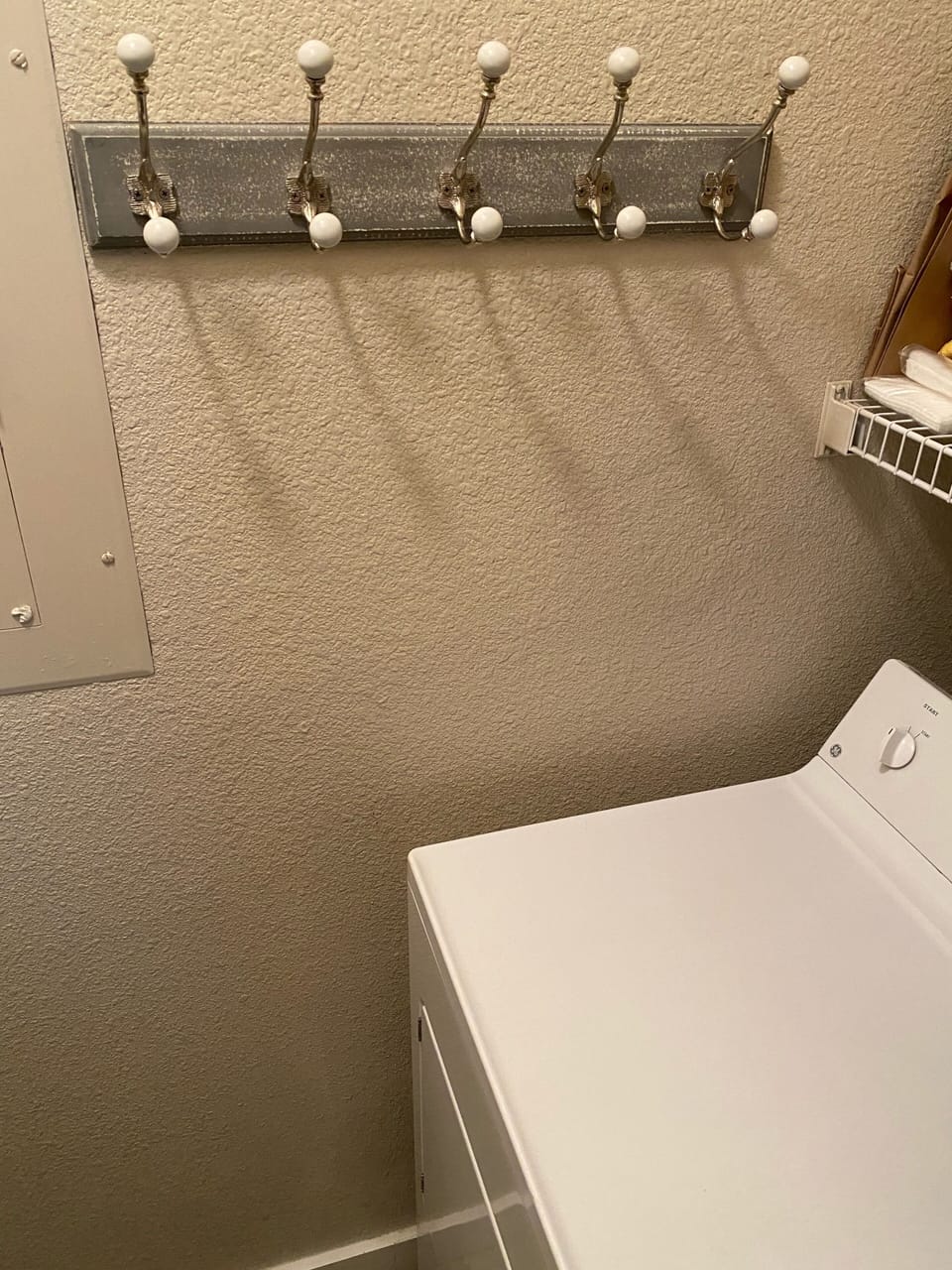 Dryer with hooks above. Separate laundry room off the kitchen.