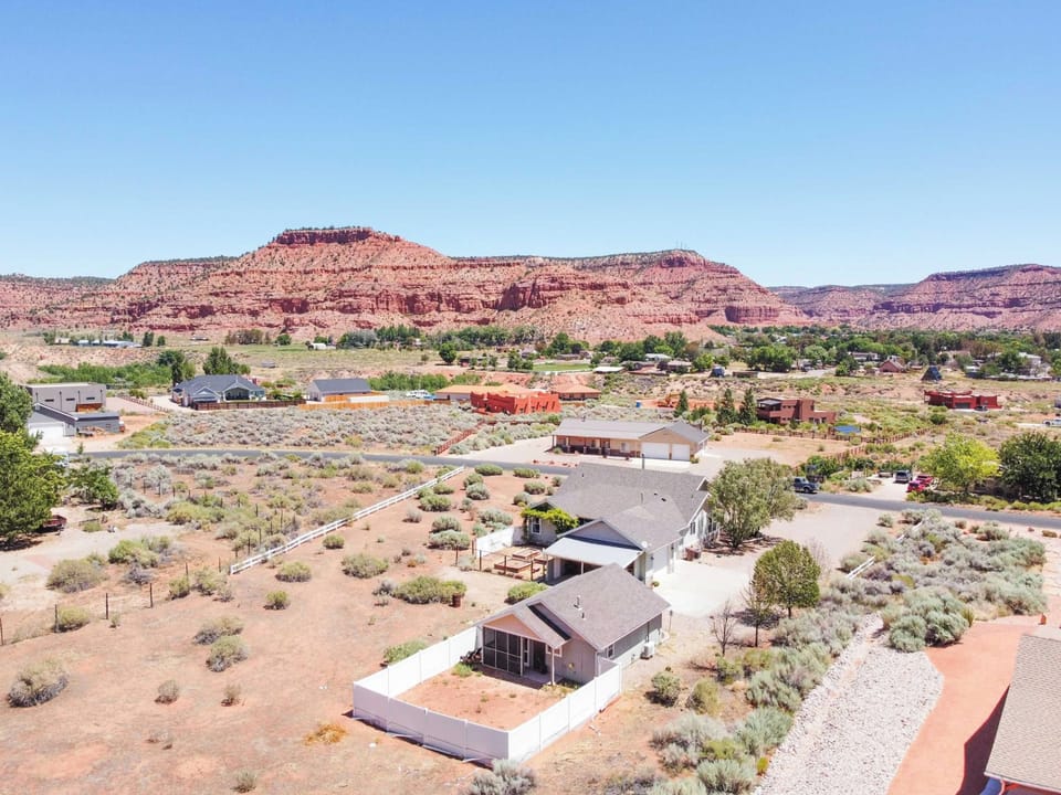Bird's-eye view of Midnight Manor's fenced backyard framed by Kanab's stunning red rock formations.