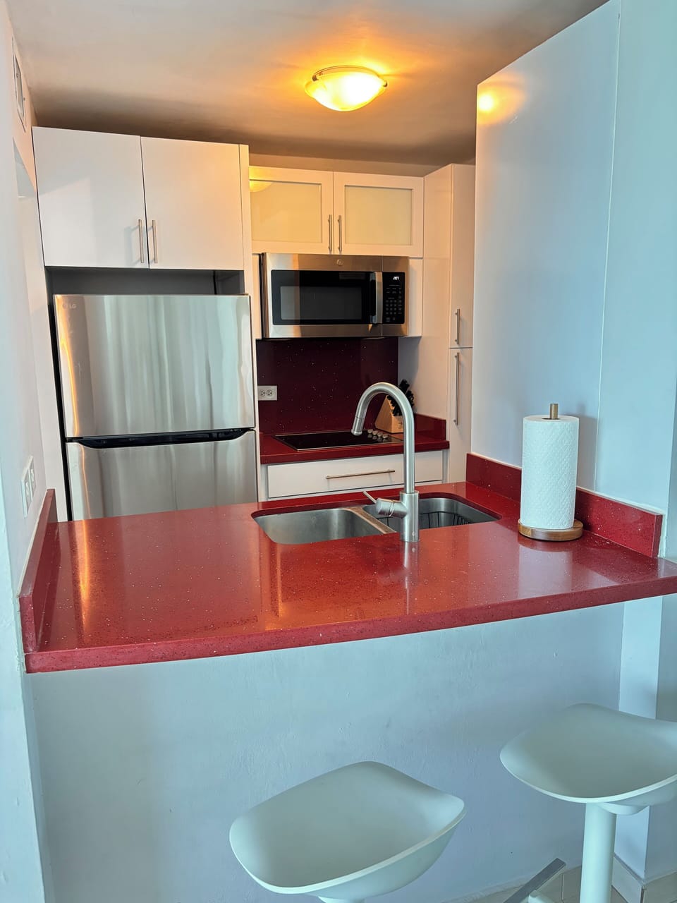 Kitchen with refrigerator, stovetop, microwave and small appliances.