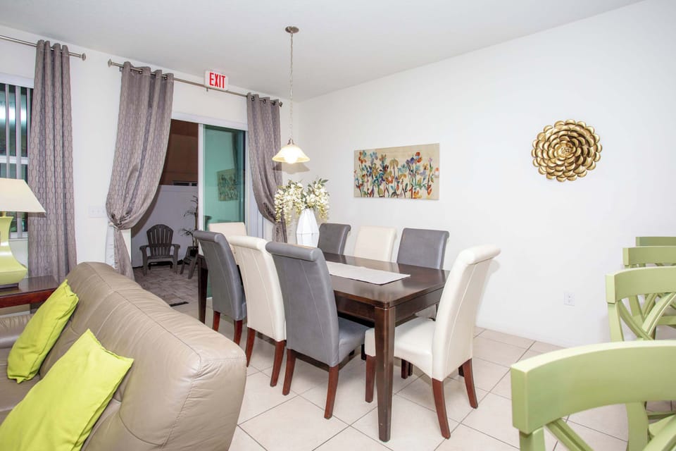 Bright open-plan living area with a lime accent wall, comfy beige seating, and a connected dining space-perfect for relaxed gatherings and everyday hangouts.