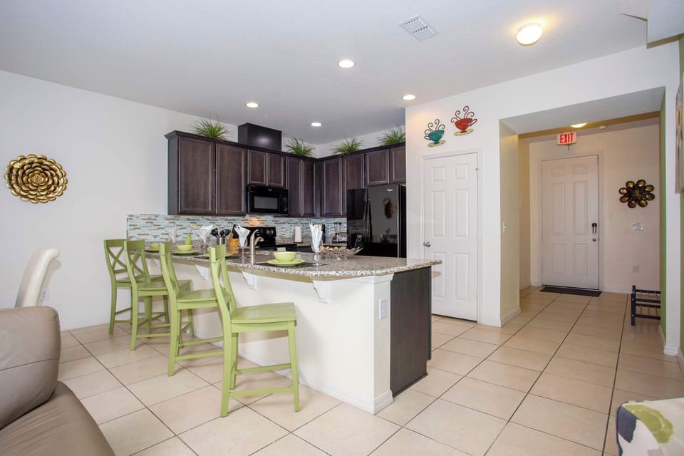 Open-concept kitchen with granite island, espresso cabinets, and stainless appliances-great for casual meals at the breakfast bar with lime-green stools.