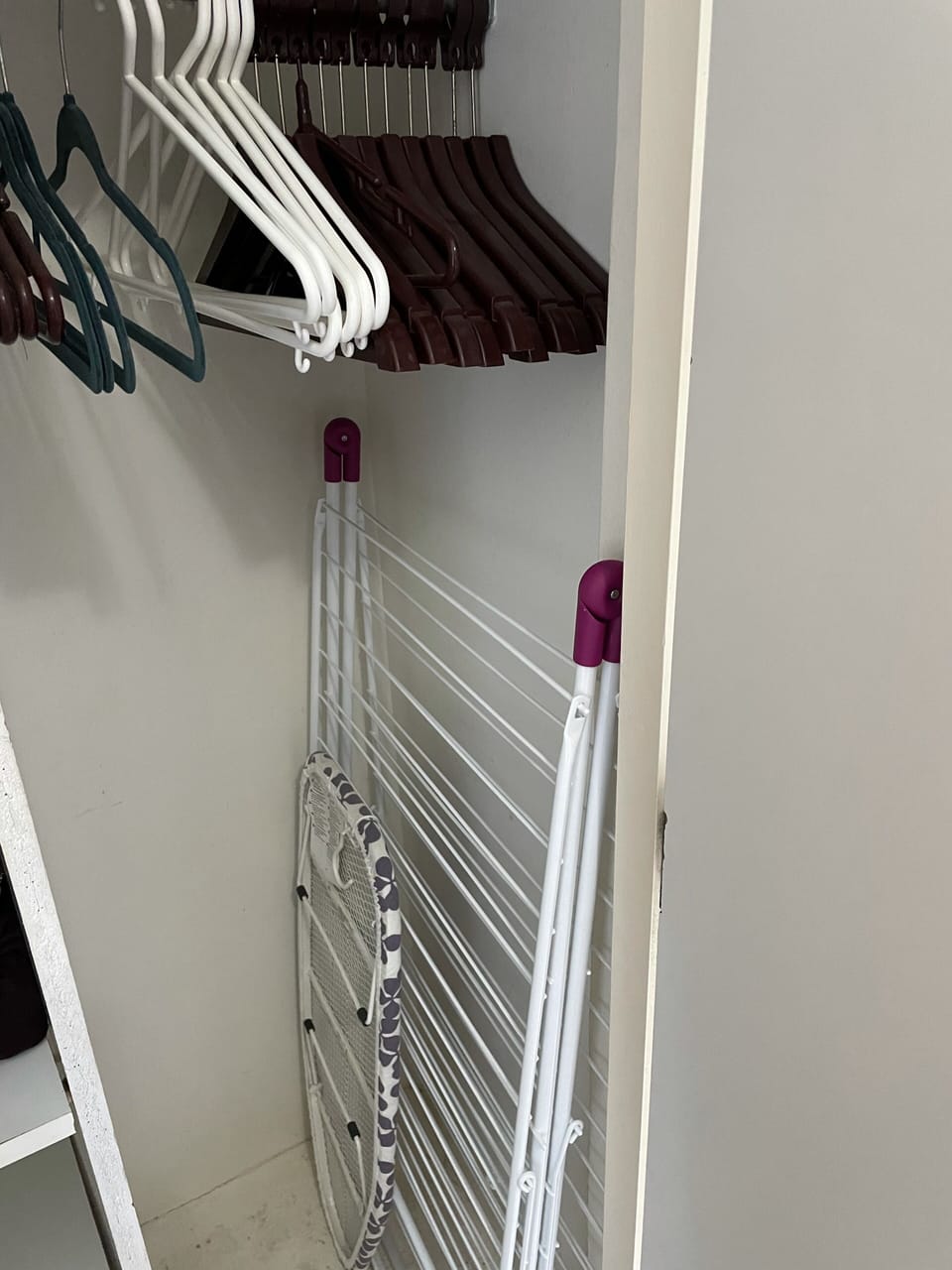 Closet with lots of hangars and shelves, drying rack,  iron & ironing board.