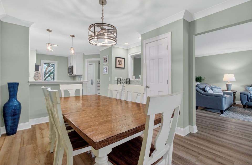 Gather around the rustic farmhouse-style dining table under elegant lighting, with the open kitchen and cozy living room just steps away—perfect for meals and making memories together.