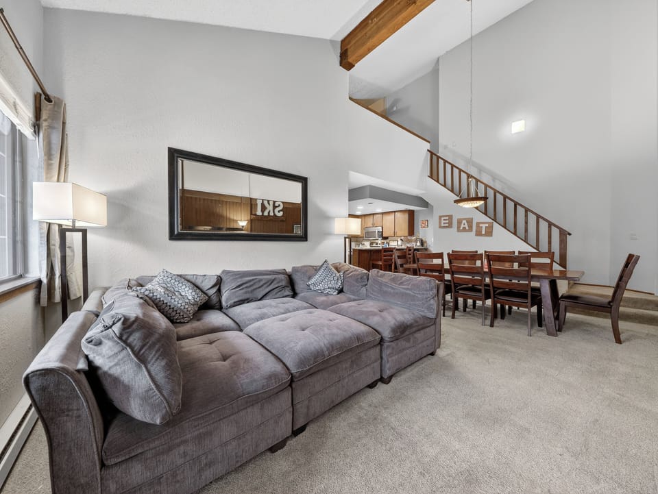 Relax in your spacious living area with plush sectional seating, high ceilings, and warm wood accents creating the perfect gathering space.