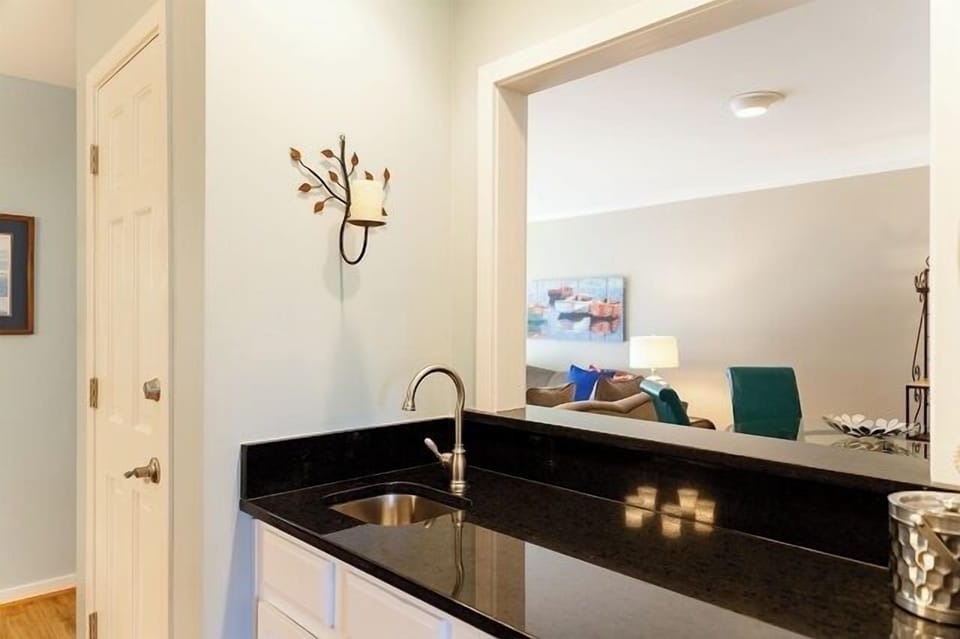 - Sleek black granite wet bar with under mount sink for easy drink prep or cleanup - Open pass through design connects kitchen and living area for seamless hosting - Elegant wall sconce adds a decorative touch to the compact bar nook