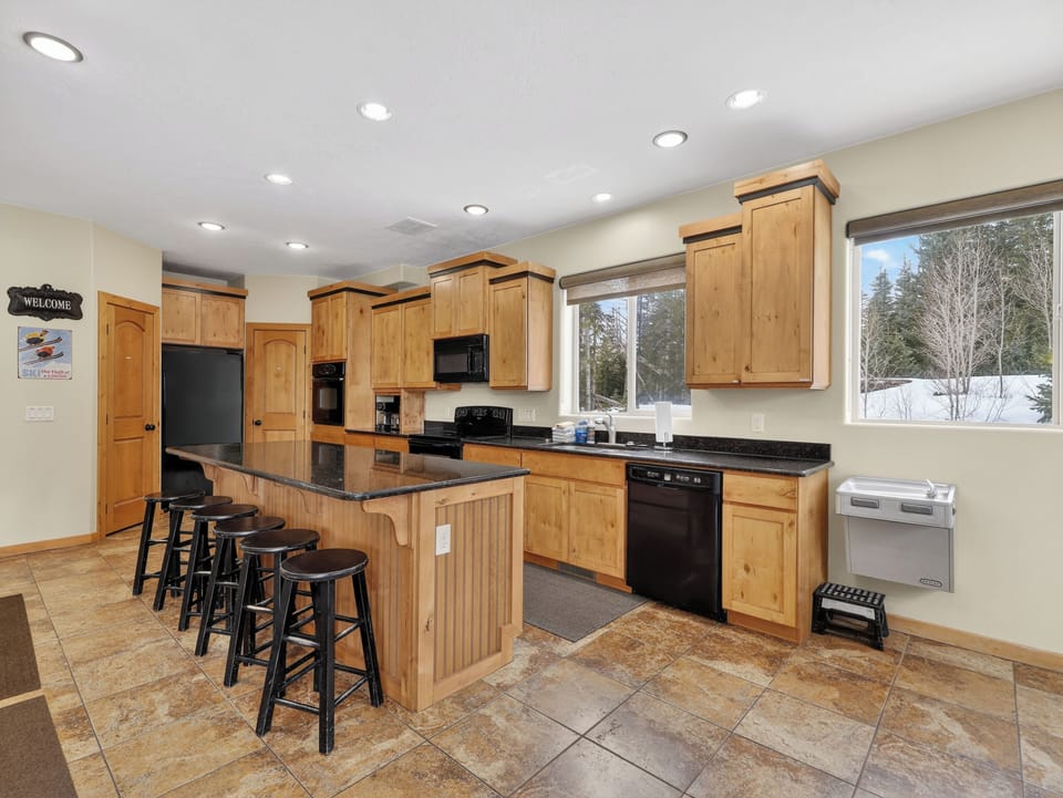 Your gourmet kitchen features granite counters, breakfast bar seating, and snowy mountain views through large windows.