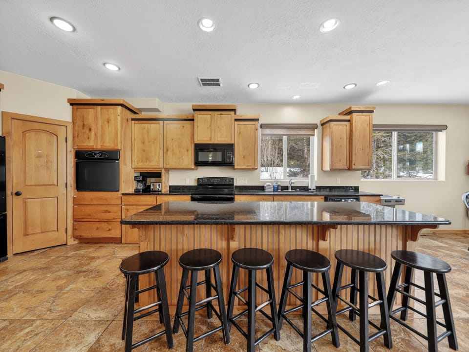 Your spacious kitchen features warm wood cabinets, granite counters, and a large island with seating for six—perfect for group meals and gatherings.