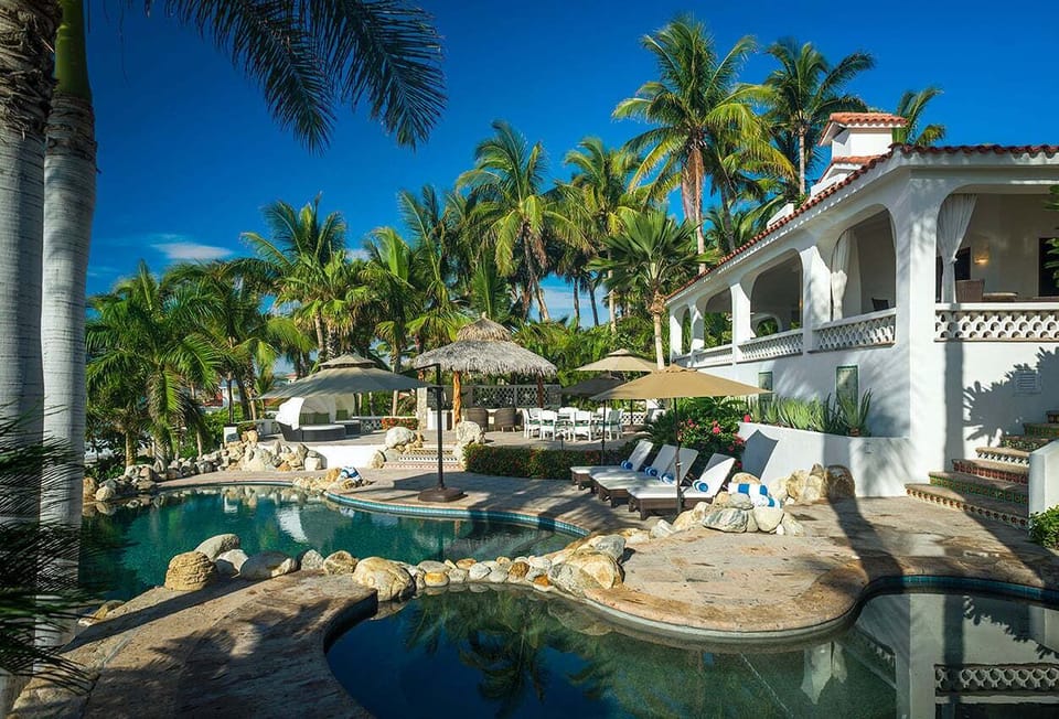 Swimming pool with natural rock features, loungers and palms at Casa Edwards, Palmilla, Los Cabos