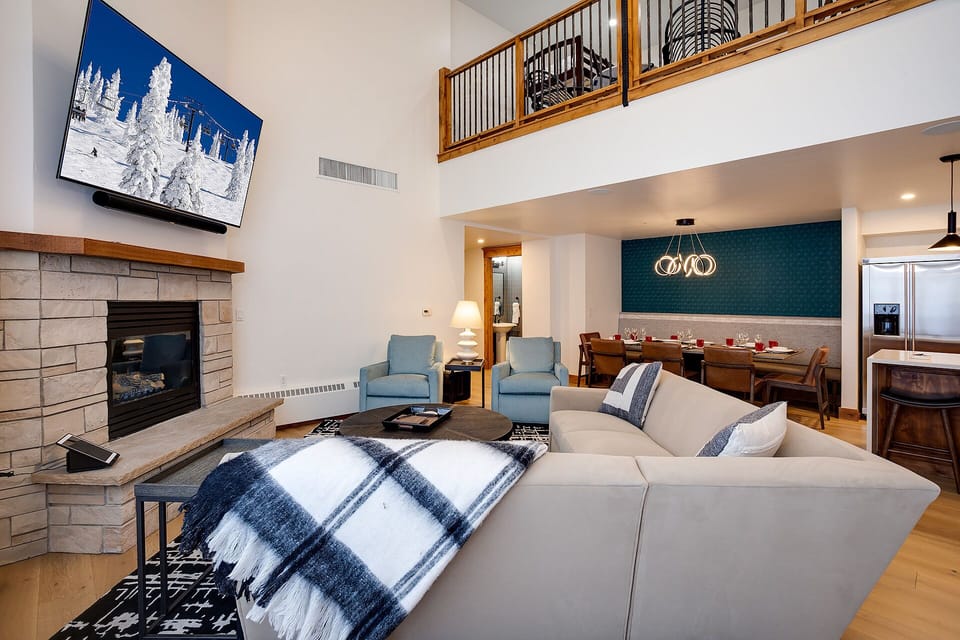 Relax in your spacious living room with soaring ceilings, cozy fireplace, and modern furnishings perfect for unwinding after mountain adventures.