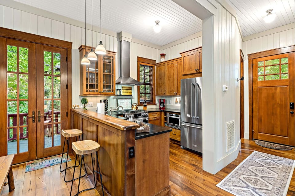 Sleek kitchen with bar seating for two, gas range stove, dishwasher, and drip-style coffeemaker.