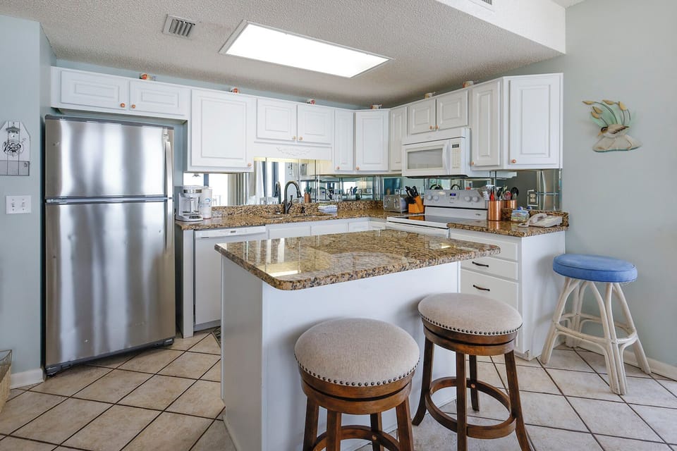 White cabinetry and a spacious island with bar stools create an inviting atmosphere in this stylish kitchen area
