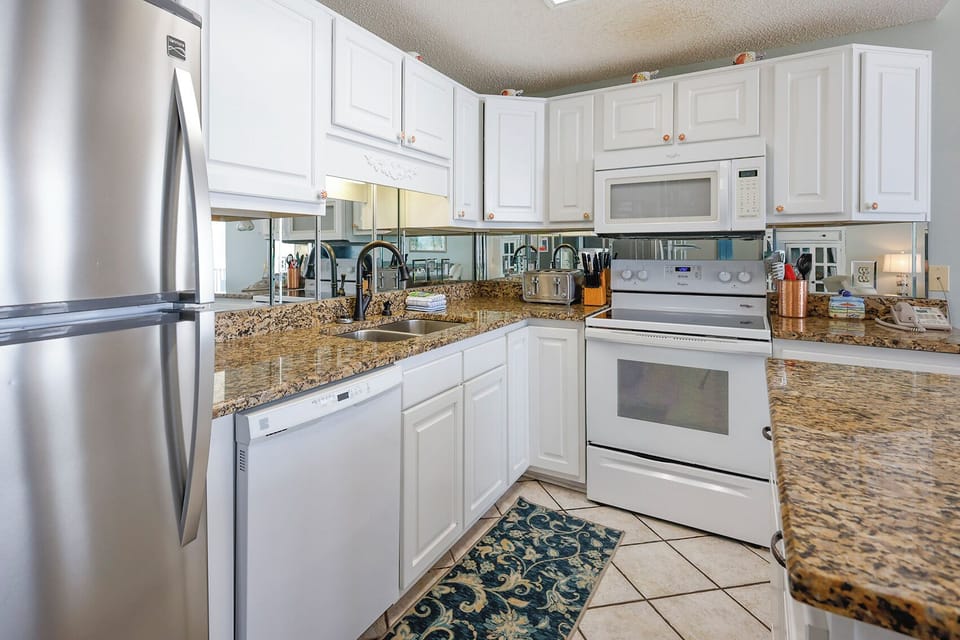 Granite countertops and white cabinetry in this inviting kitchen, featuring a spacious design for beach meals