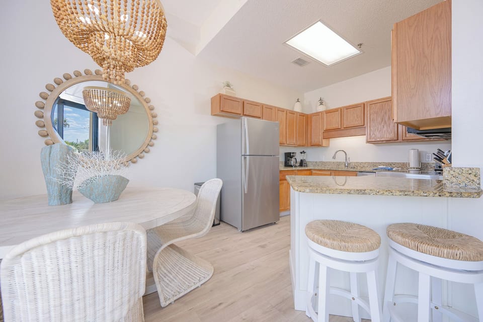 Prepare meals in this kitchen featuring granite countertops, stainless and white appliances, and inviting seating
