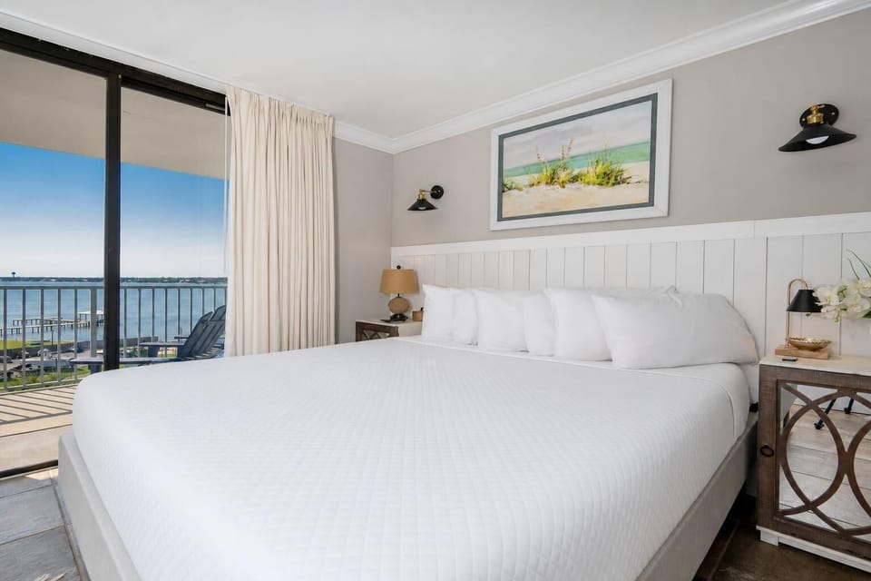 Master bedroom featuring a plush king bed and stunning views of the water through large sliding glass doors