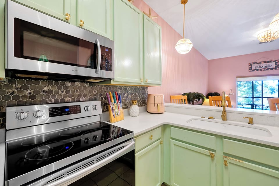Another view of the fully equipped kitchen — tropical style meets modern convenience with stainless appliances and bright quartz counters.
