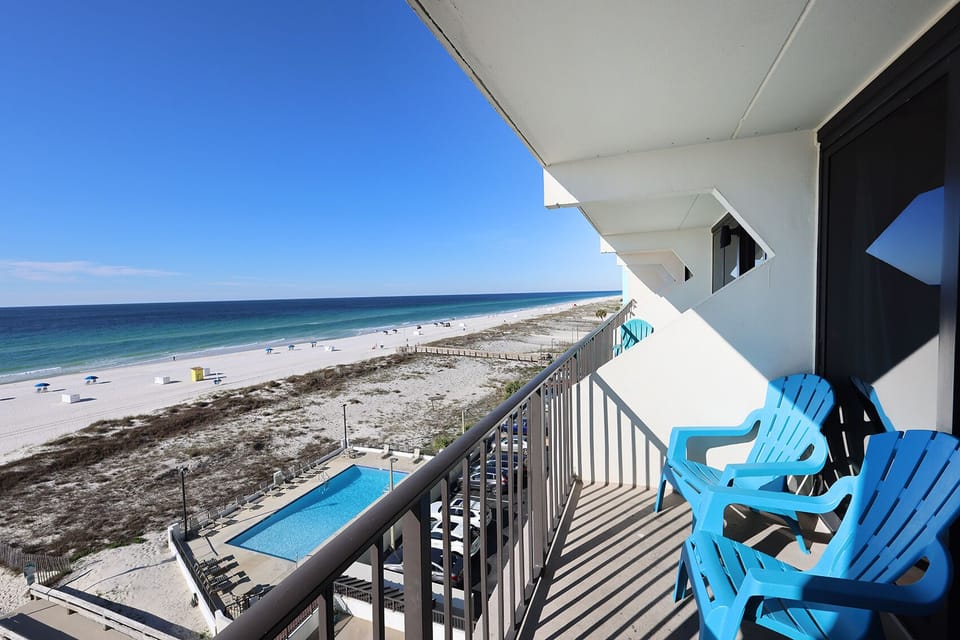 Enjoy stunning beachfront views from this balcony, complete with comfortable seating and a glimpse of the inviting pool below