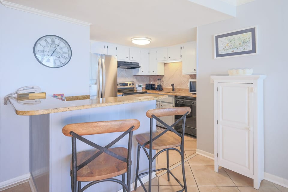 This elegant kitchen features sleek stainless appliances, a breakfast bar with seating, and a light, airy atmosphere