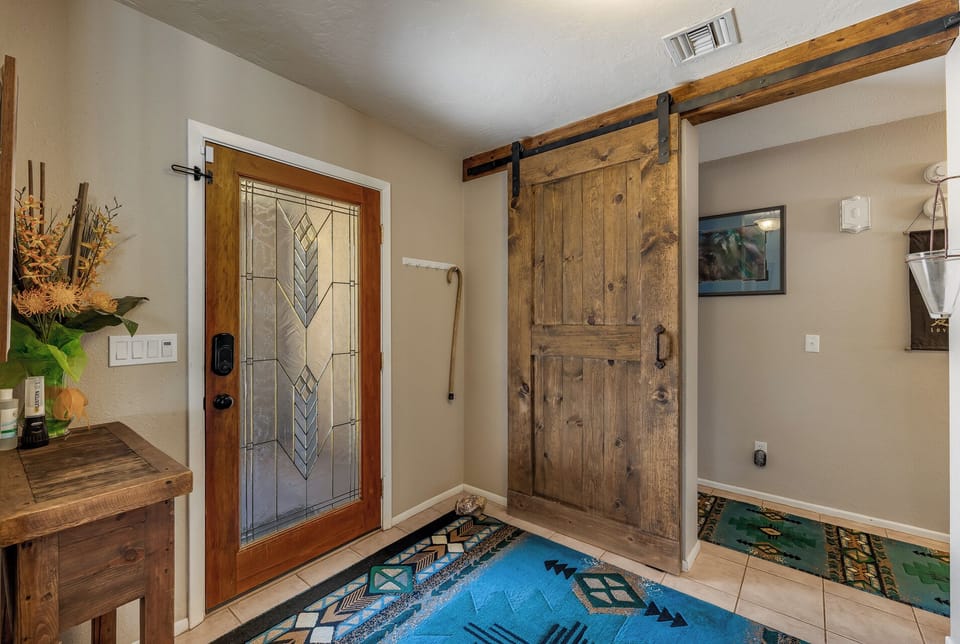 view from greatroom to entry door and barn door to bedroom wing