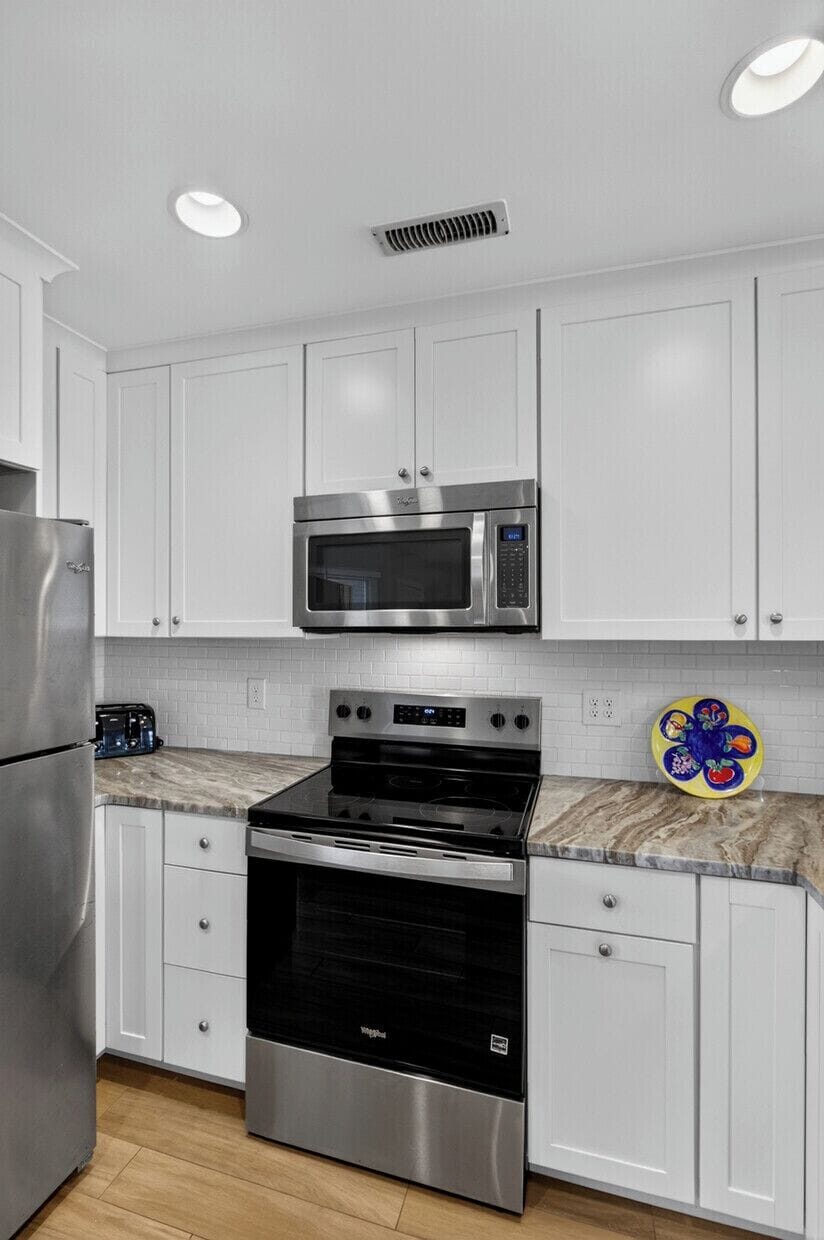 Step into your fully equipped kitchen, featuring stainless steel appliances and stylish white cabinetry. Whip up your favorite meals on the modern stove and enjoy all the comforts of home during your stay.