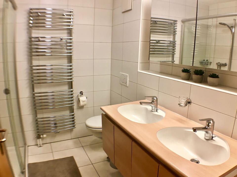 Bathroom with two sinks, heated towel rack and large walk-in shower
