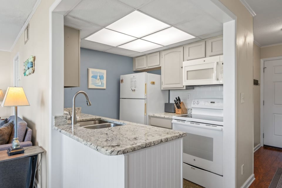 Picture yourself prepping meals in this fully-equipped kitchen with granite countertops, stainless sink, and bright skylight illuminating your culinary creations. Modern appliances make cooking effortless.