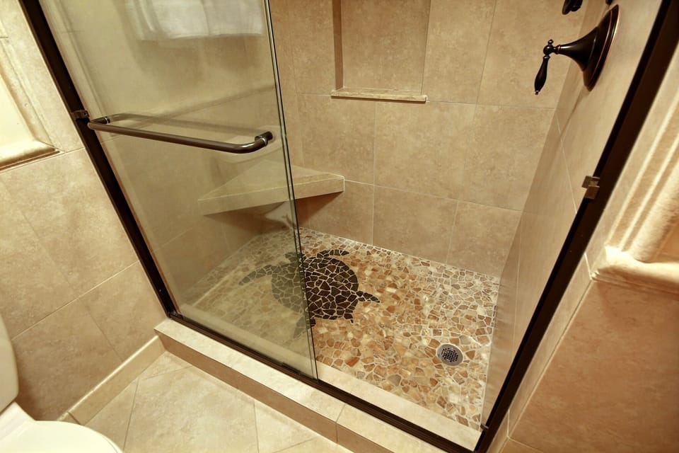 A large spa-like shower with an inlayed green turtle in the river-rock floor.
